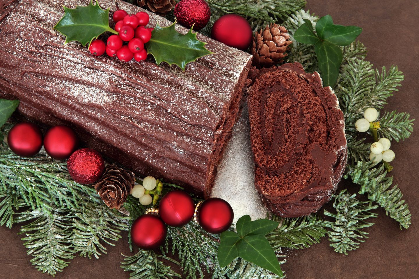 A bûche de noël or Yule log surrounded with Christmas decorations
